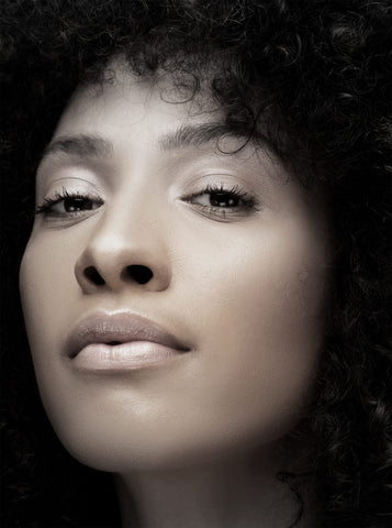 A black woman with curly hair is posing for a photo.